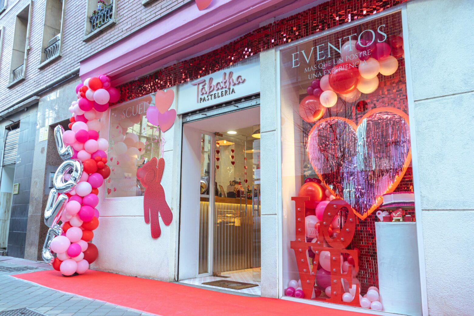 escaparate de san valentín decoración con globos rojos rosas y shimmer wall en madrid para la fachada de tabatha pastelería