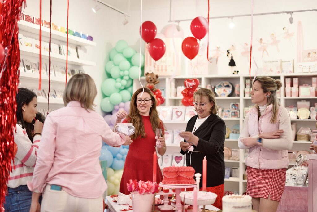 galentine's day, juegos entre amigas, sonrisas, dinamicas de grupo, mujer vestido rojo y mujer pantalon rojo leen un mensaje en la fiesta de galentine's day